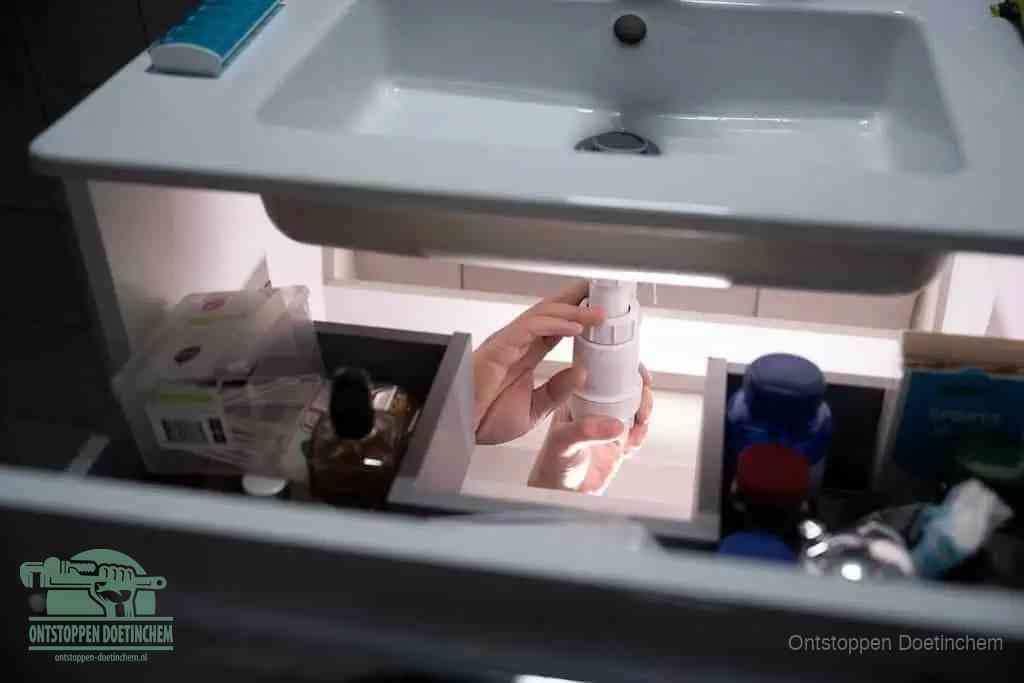 Een pompfles met zeep boven een wastafel, de heet water en afwasmiddel-methode om een vetprop in de afvoer los te maken in Doetinchem