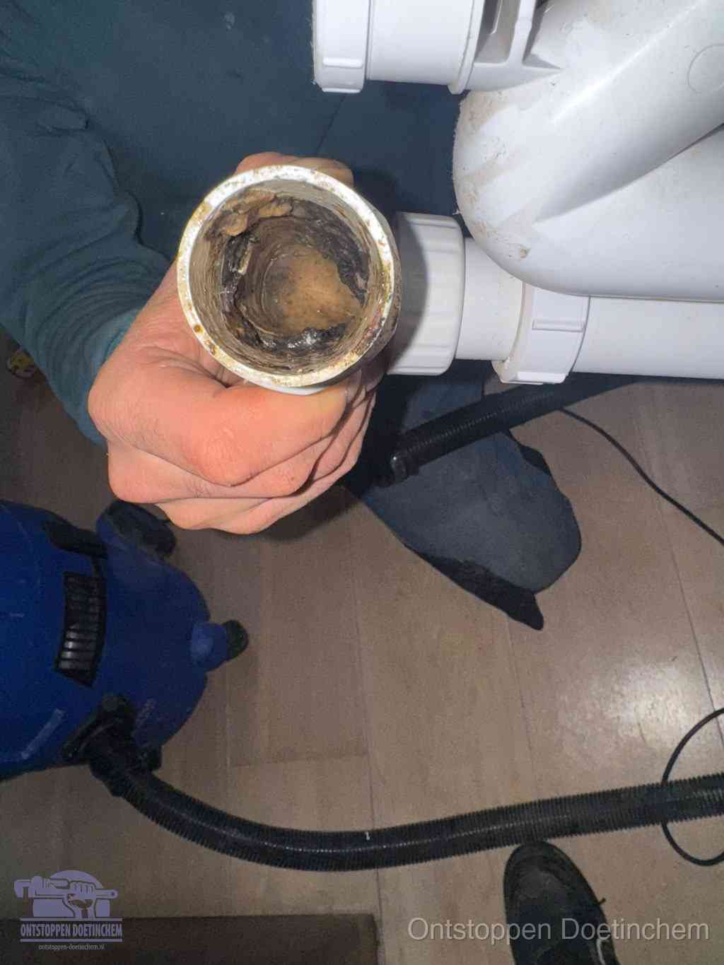 Een losgekoppelde afvoerbuis die van binnen volledig is dichtgeslibd met vet en aanslag, de meest voorkomende oorzaak van een verstopte gootsteen in Doetinchem