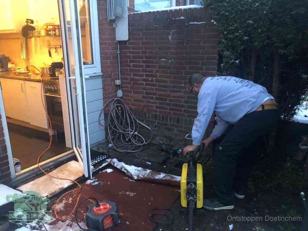 Een monteur werkt buiten bij een open riool-/grondput met een elektrische ontstoppingsmachine om een verborgen afvoerprobleem op te sporen in Doetinchem