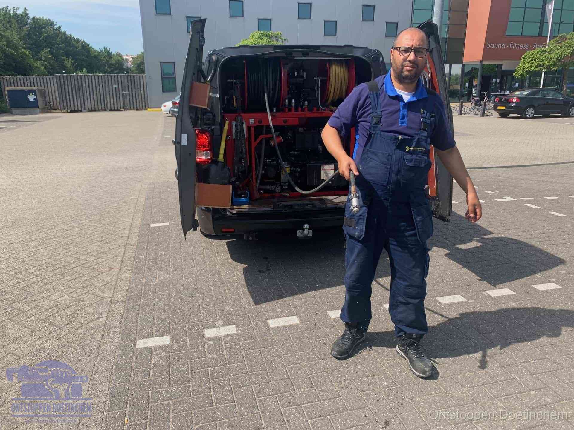 Een monteur bij zijn bestelbus met een hogedruk- en rioolreinigingsunit, klaar om de oorzaak van terugkerende wc-verstoppingen aan te pakken in Doetinchem