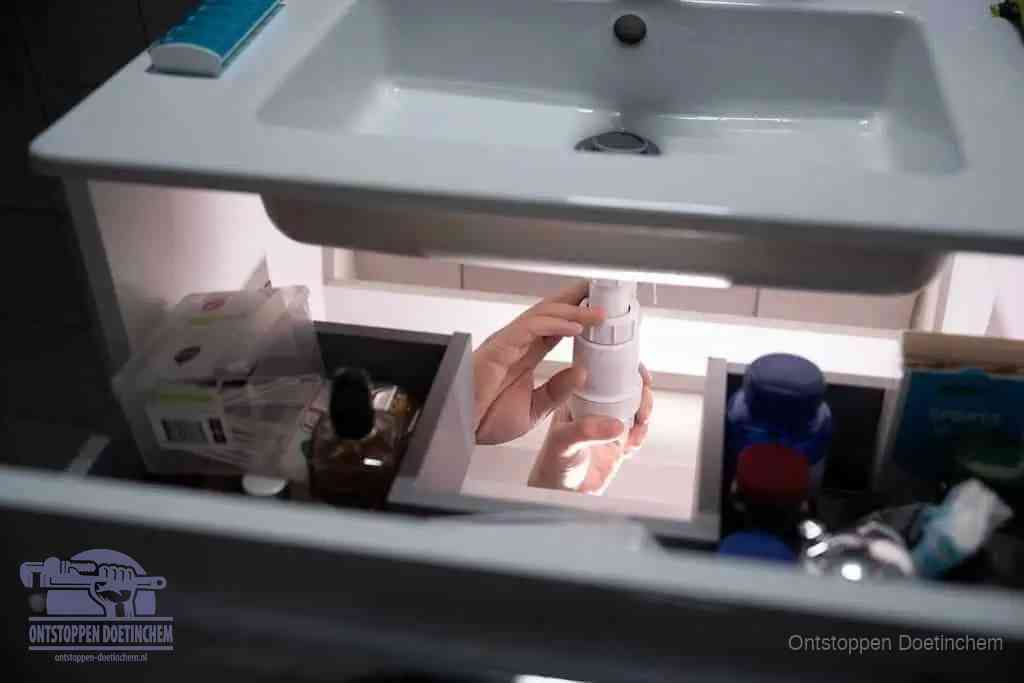 Een pompfles met zeep boven een wastafel in de toiletruimte, de warm water en afwasmiddel-methode om de wc te ontstoppen in Doetinchem
