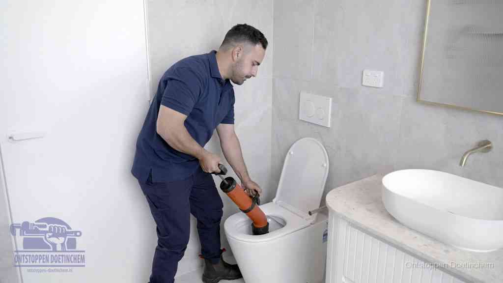 Een monteur gebruikt een handmatige perspomp (toiletontstopper) op een wandcloset tijdens het professioneel wc ontstoppen in Doetinchem